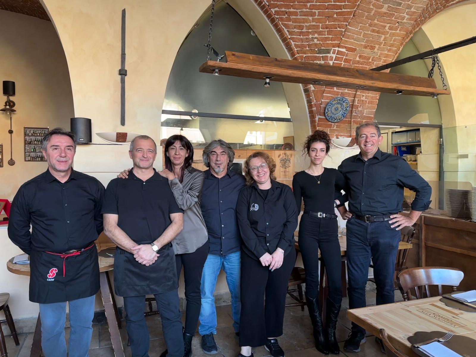 Gruppo di personale di un ristorante in posa insieme in un ambiente interno con soffitti a volta.
