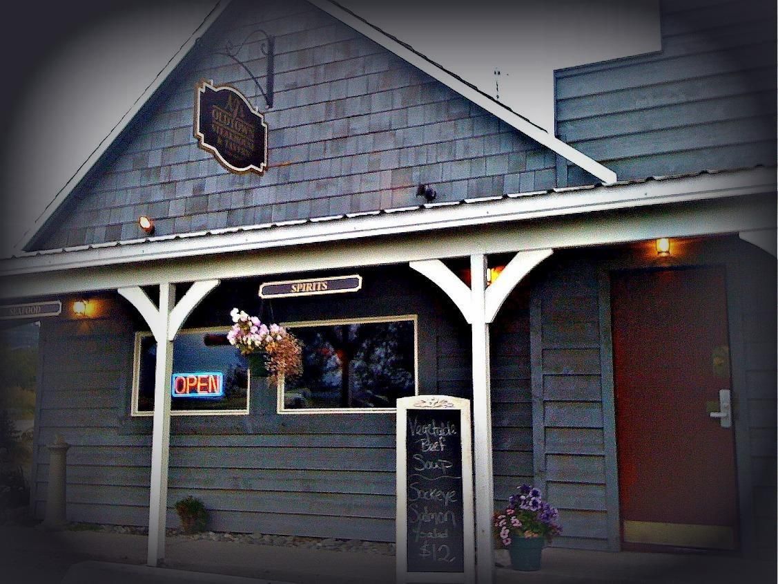 Gray building with porch; sign and chalkboard, door on right.
