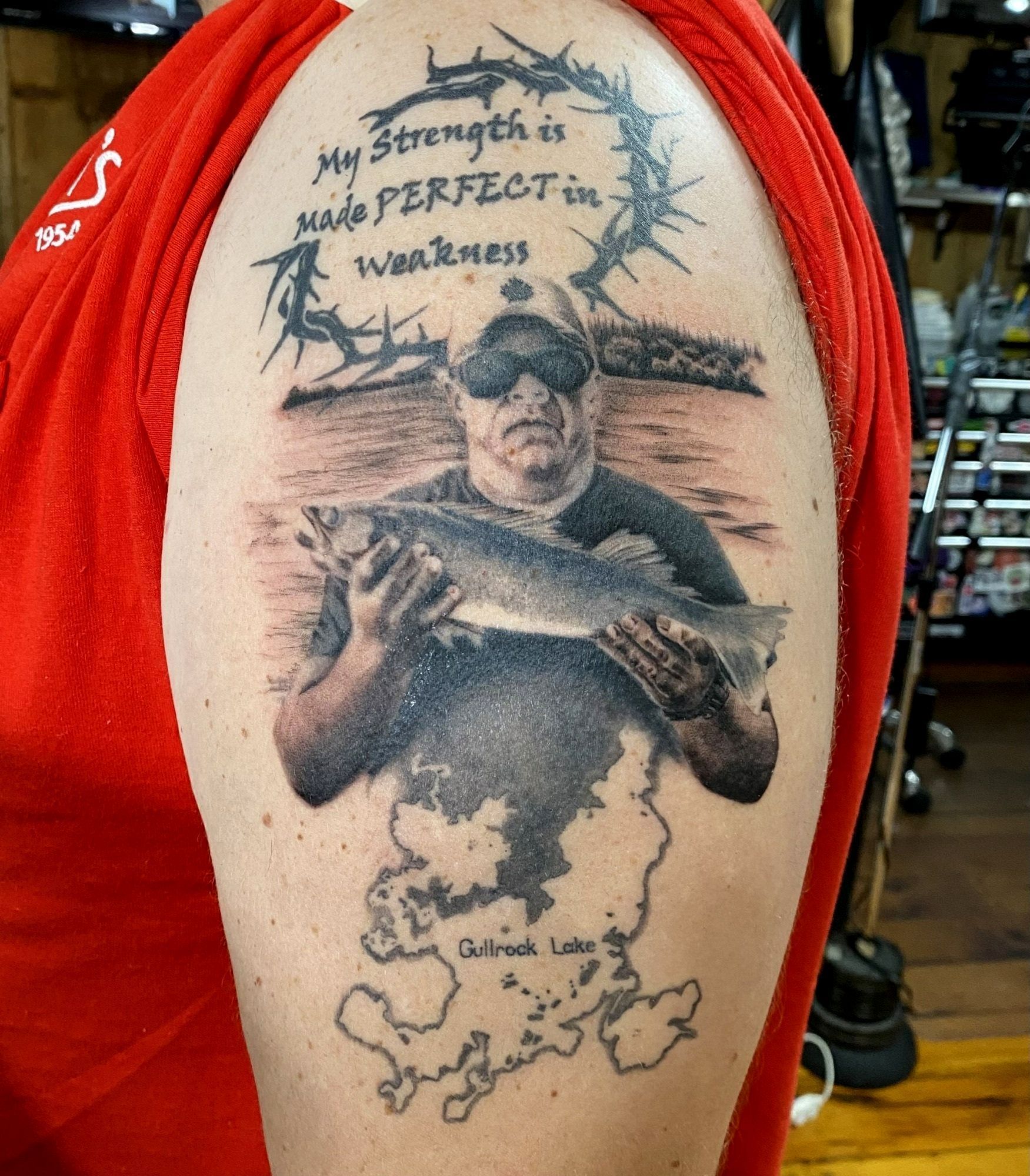 Tattoo: Man holding fish, map of Lake, and text, 