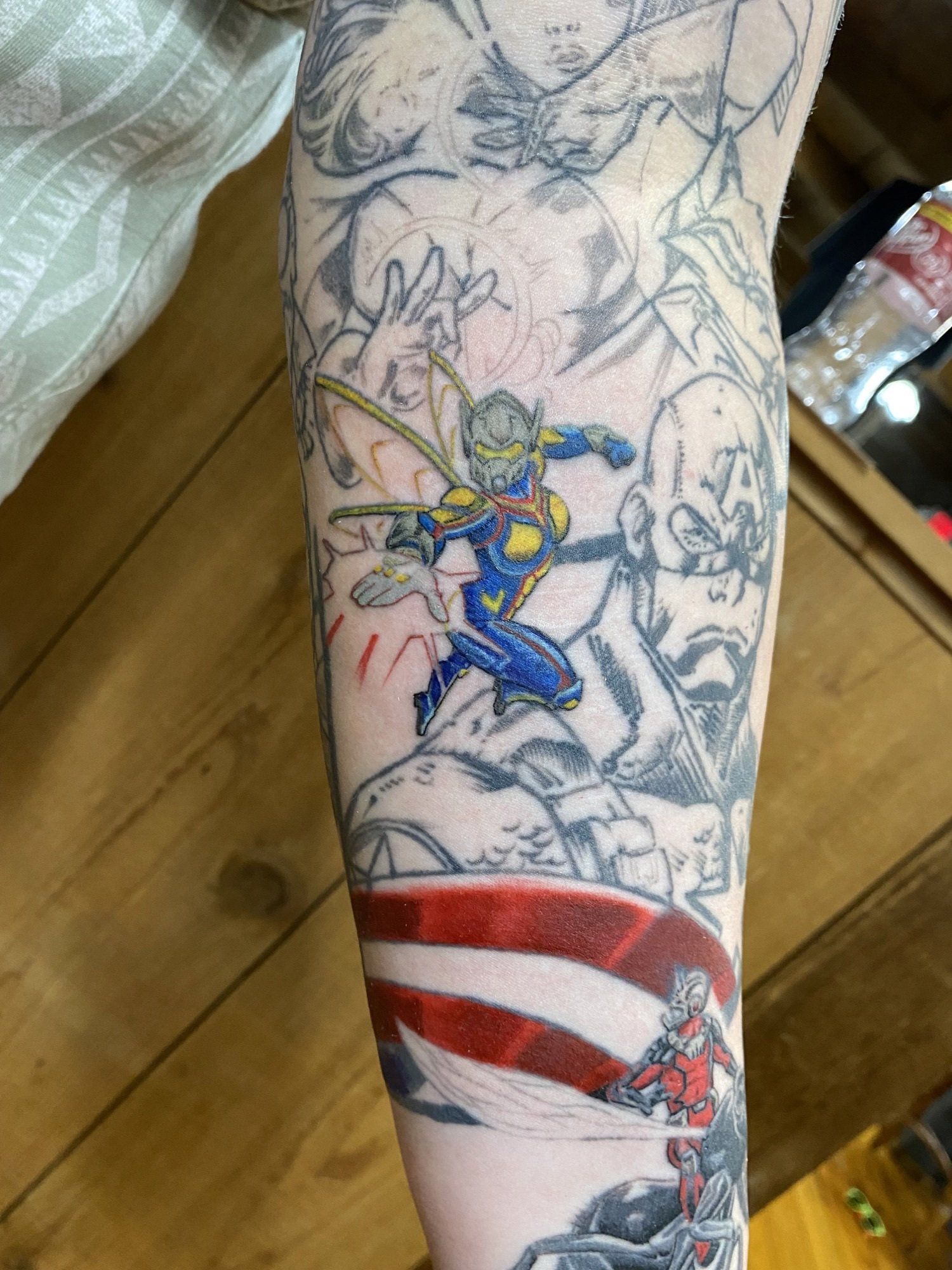 Marvel comic-themed tattoo in progress on arm; Wasp in color, Captain America, Ant-Man in gray, and red shield.
