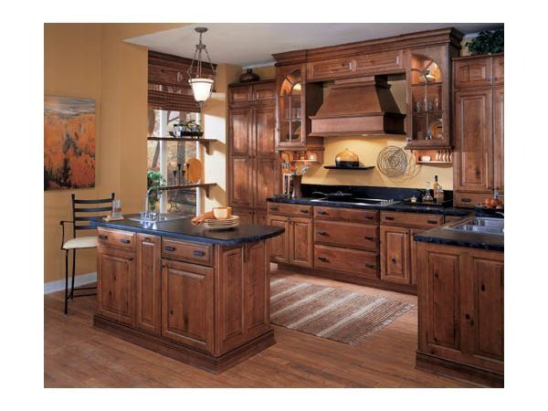 Rustic kitchen with dark wood cabinets, island, and countertops. Yellow walls, wood floors, and rug.