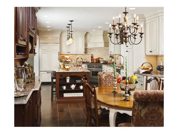 Elegant kitchen with dark wood cabinets and island, light cabinets, and dining table set.