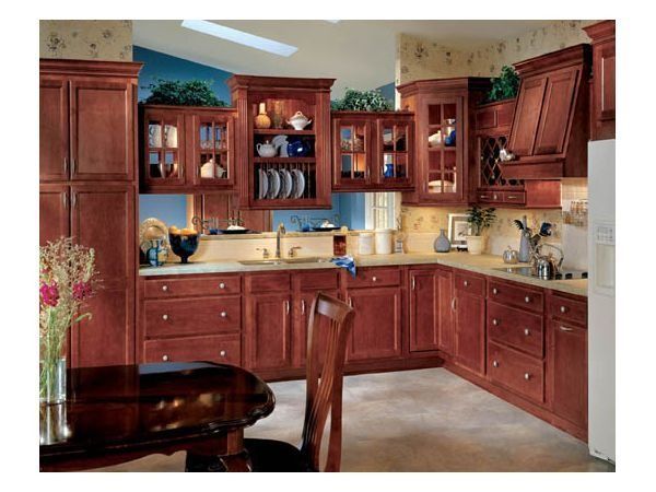 Kitchen with reddish-brown wooden cabinets and countertops, glass-fronted upper cabinets, and a dining table.
