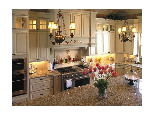 Oval bathtub in a bathroom, next to two windows with blinds. Gold faucet, white cabinetry and wall, beige walls.