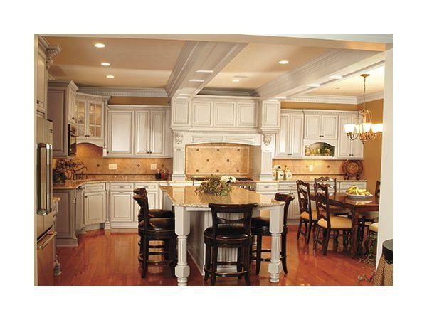 Elegant white kitchen with wood floors, island, cabinets, and dining area.