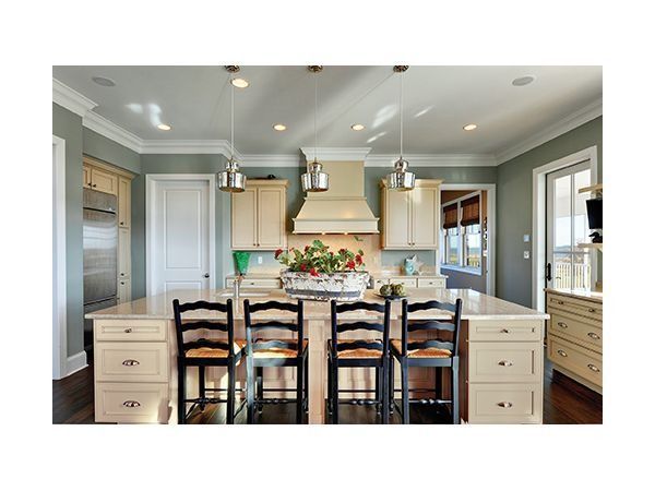 Kitchen with island and chairs, light cabinets, stainless steel appliances, and pendant lighting.