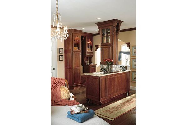 Elegant kitchen with dark wood cabinetry, island, and decorative chandelier.