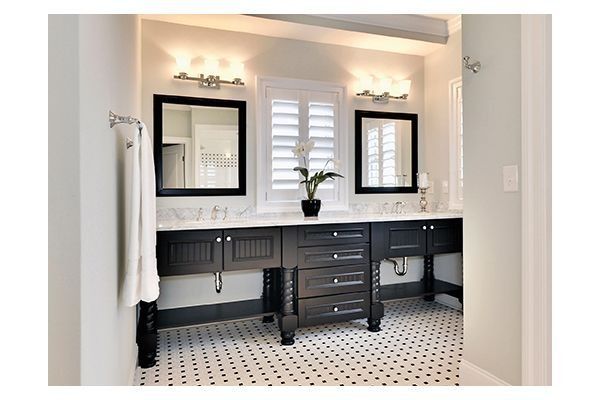 Bathroom with black vanity, mirrors, and white countertops. White shutters and black and white tiled floor.