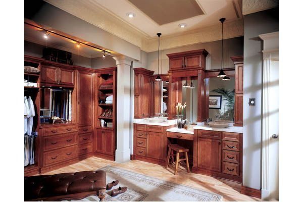 Walk-in closet with dark wood cabinetry, vanity, and a light-colored rug on the floor.