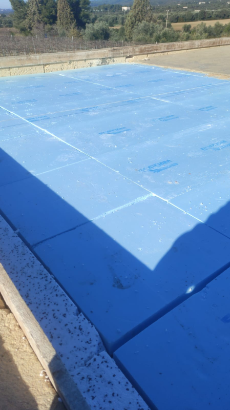 Superficie esterna ricoperta di blu o area piscina adiacente a un bordo in cemento in un paesaggio soleggiato