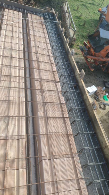 Cantiere edile con armature in ferro e casseforme in legno per una soletta in cemento su un tetto