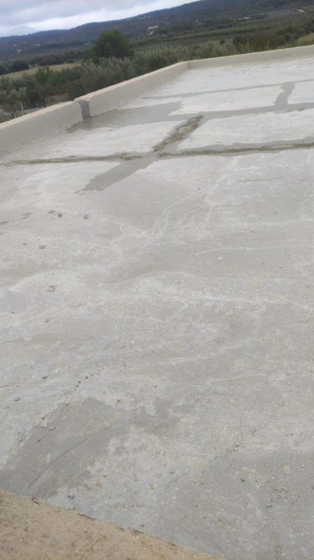 Superficie di cemento screpolata con un paesaggio montano in lontananza sotto un cielo nuvoloso.