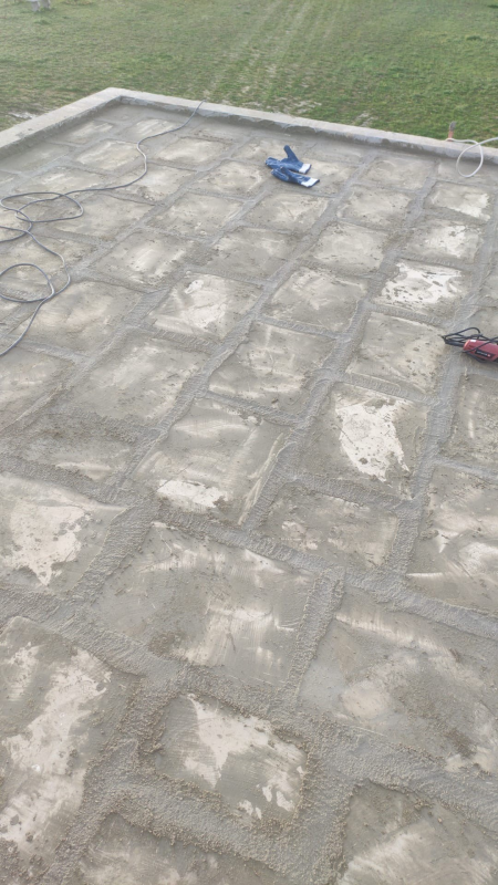 Patio in pietra con due piccole scarpe sopra, accanto a un prato erboso.