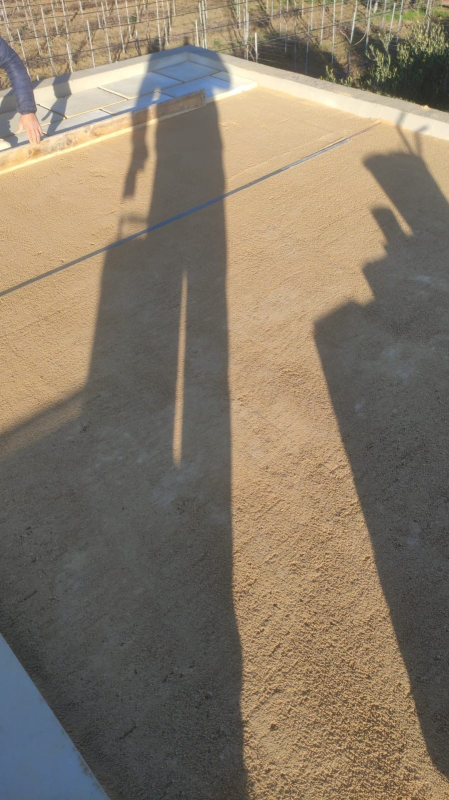 Lunghe ombre di due persone si allungano su una passerella di cemento color beige vicino a una ringhiera.