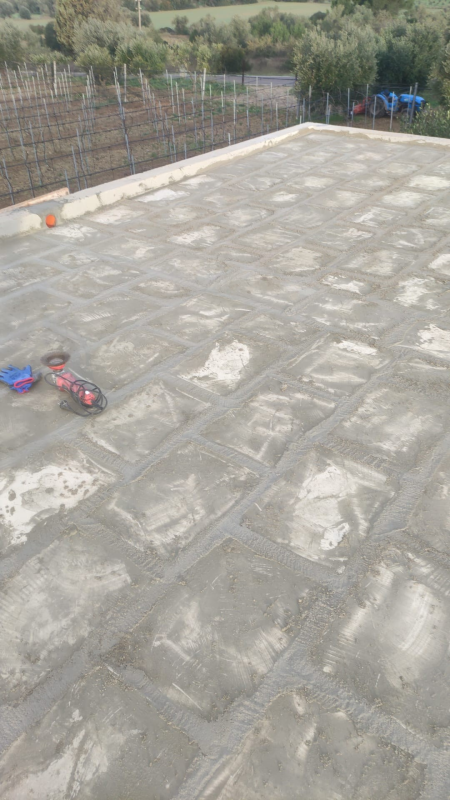 Tetto in cemento con un piccolo giocattolo per bambini vicino al bordo sinistro e una recinzione lungo il retro.