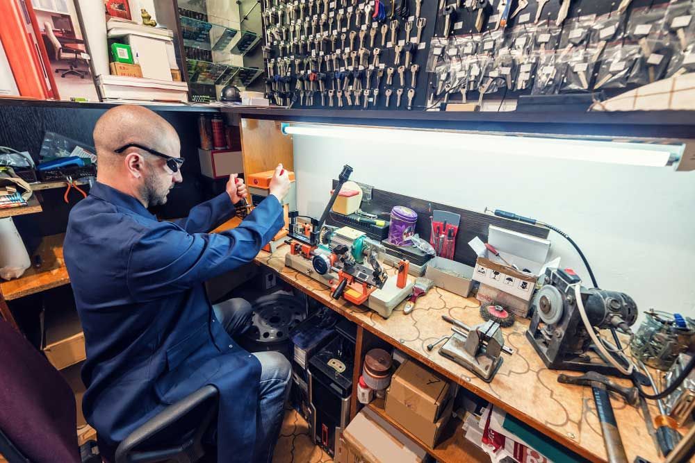 A man in a blue coat is working on a machine — Border Locksmiths & Electronics In Tweed Heads, NSW