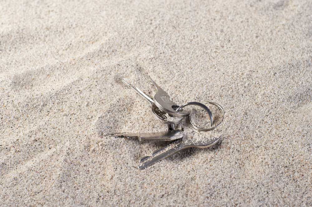A bunch of keys laying on top of a pile of sand — Locksmith in Surfers Paradise, QLD