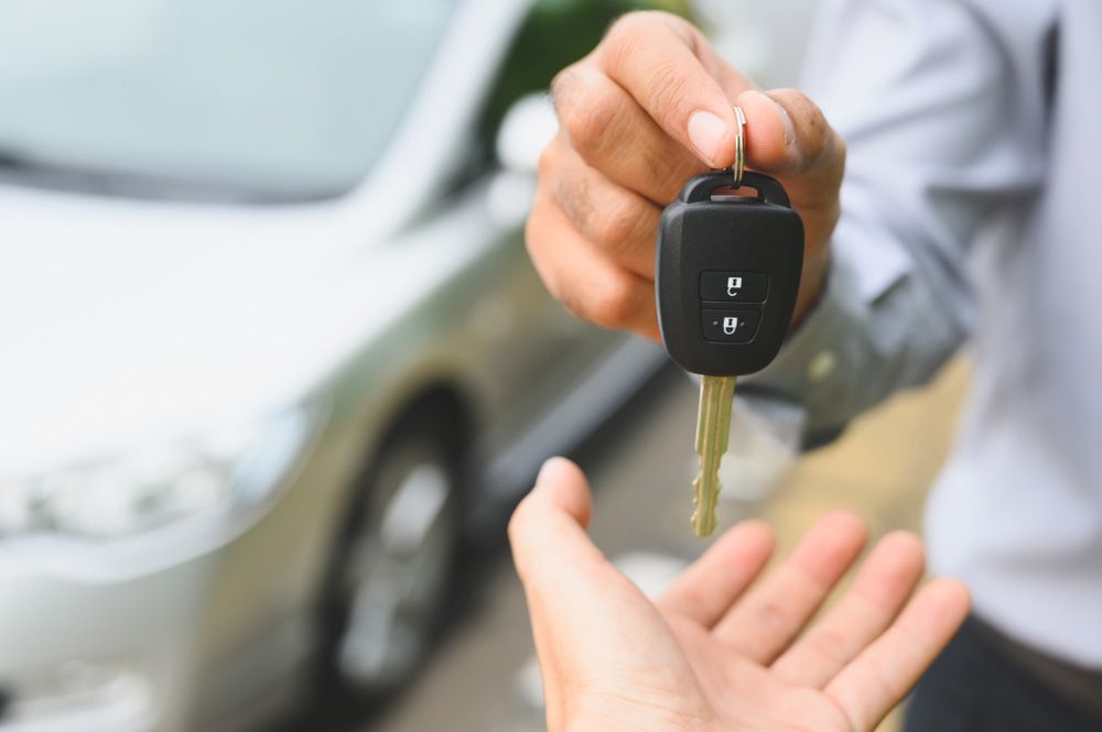 A person is handing a car key to another person — Locksmith in Nerang, QLD