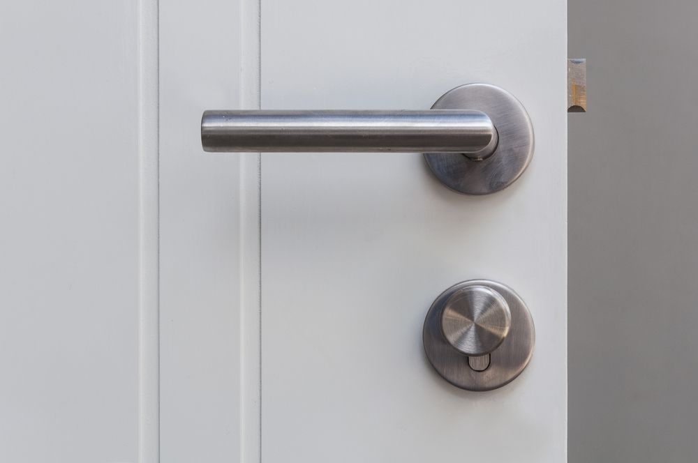 A stainless steel door handle on a white door — Locksmith in Tweed Heads, NSW