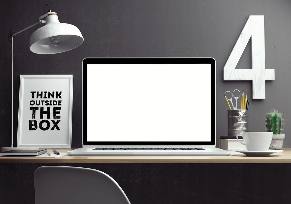 A laptop computer is sitting on a desk next to a sign that says think outside the box — Locksmith in Tweed Heads, NSW