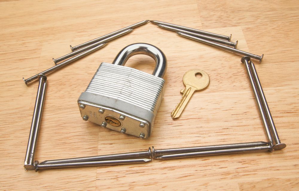A padlock and a key are surrounded by nails in the shape of a house — Locksmith in Coolangatta, QLD