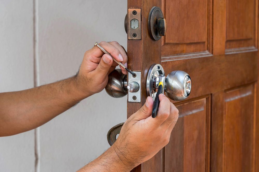 A man is fixing a door with a screwdriver — Locksmith in Tweed Heads, NSW