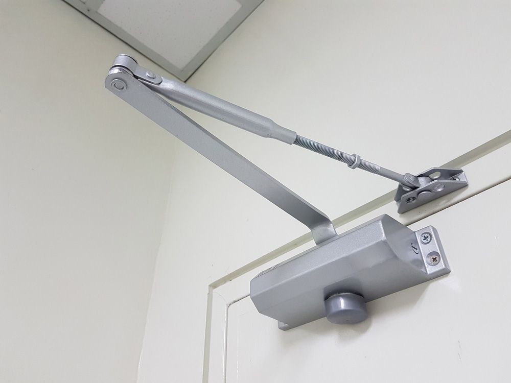 A close up of a door closer on a white wall — Locksmith in Tweed Heads, NSW