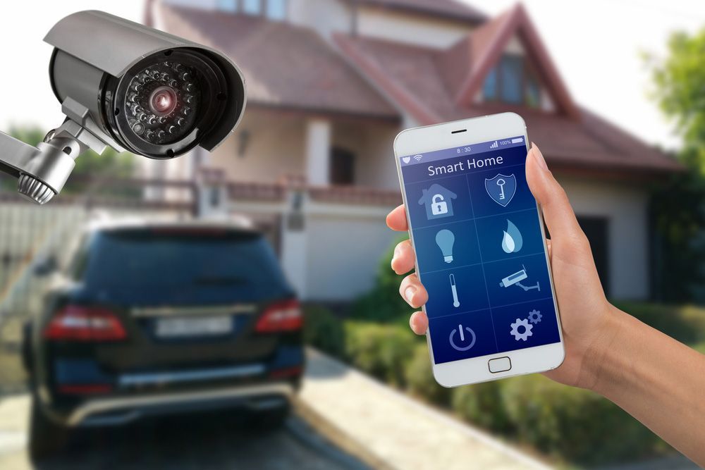 Person holding a smart home phone in front of a house — Locksmith in Tweed Heads, NSW