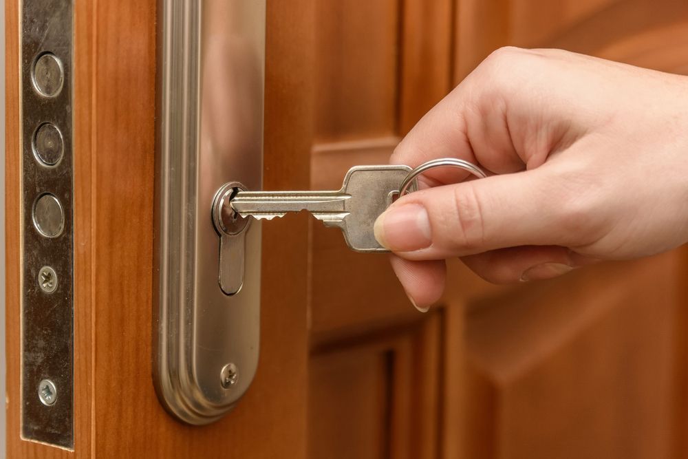 A hand is holding a key in a door lock — Locksmith in Currumbin, QLD