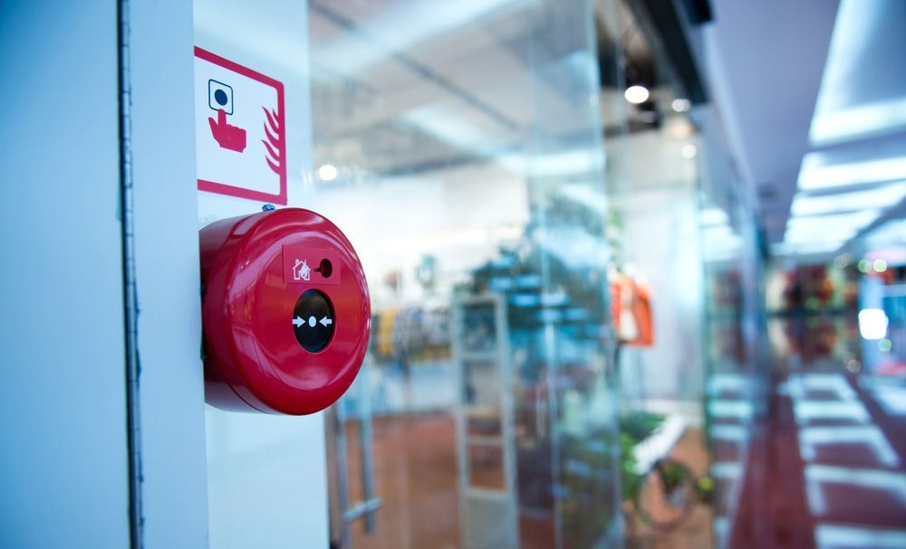 A red fire alarm is on a glass door — Locksmith in Brisbane, QLD