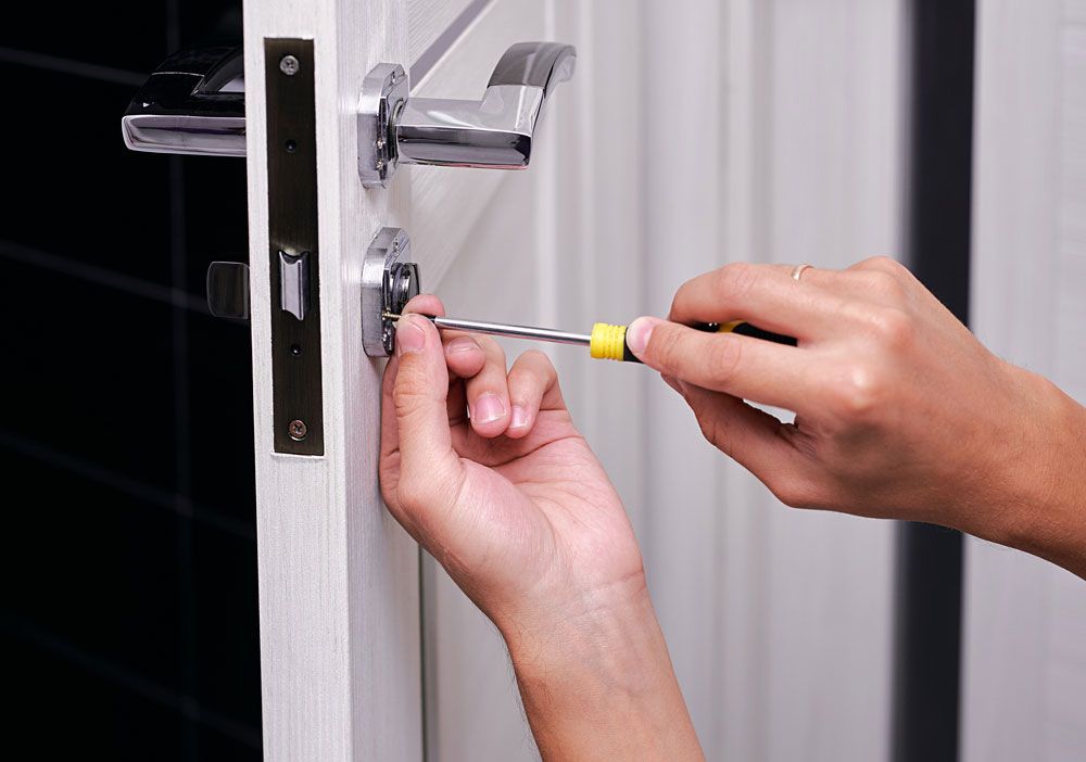 Locksmith is fixing a door with a screwdriver — Locksmith in Tweed Heads, NSW