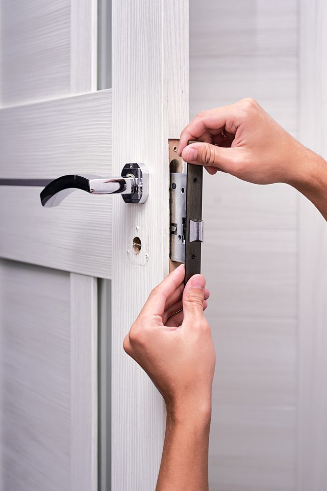 A person is installing a door lock on a white door — Locksmith in Nerang, QLD