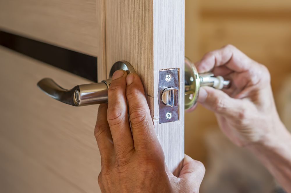 A person is installing a door handle on a wooden door — Locksmith in Surfers Paradise, QLD
