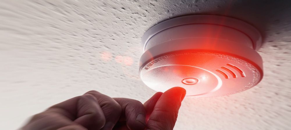 A person is pressing a button on a fire alarm — Locksmith in Nerang, QLD