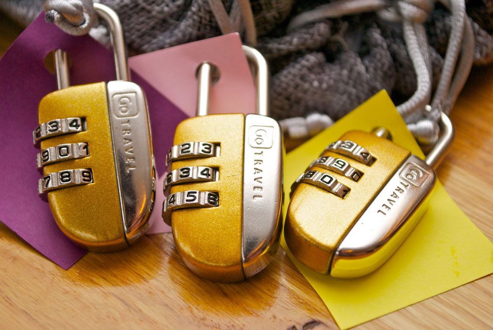 Three gold go travel locks sit on a wooden table — Locksmith in Burleigh Heads, QLD