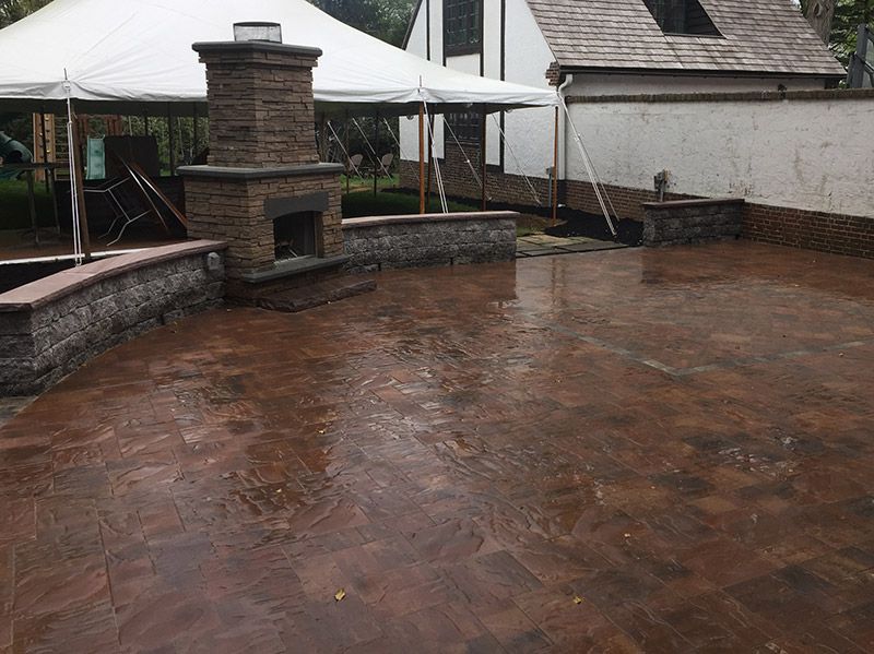 A patio with a fireplace and a white tent in the background.