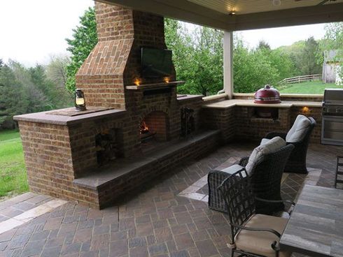 A patio with a brick fireplace and chairs