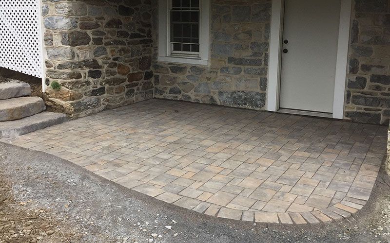 A stone building with a brick patio in front of it.
