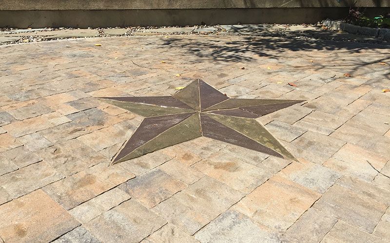 A star is carved into a brick driveway