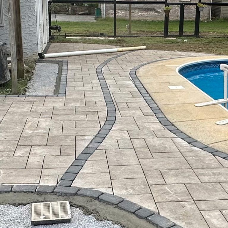 A patio with a walkway leading to a swimming pool.