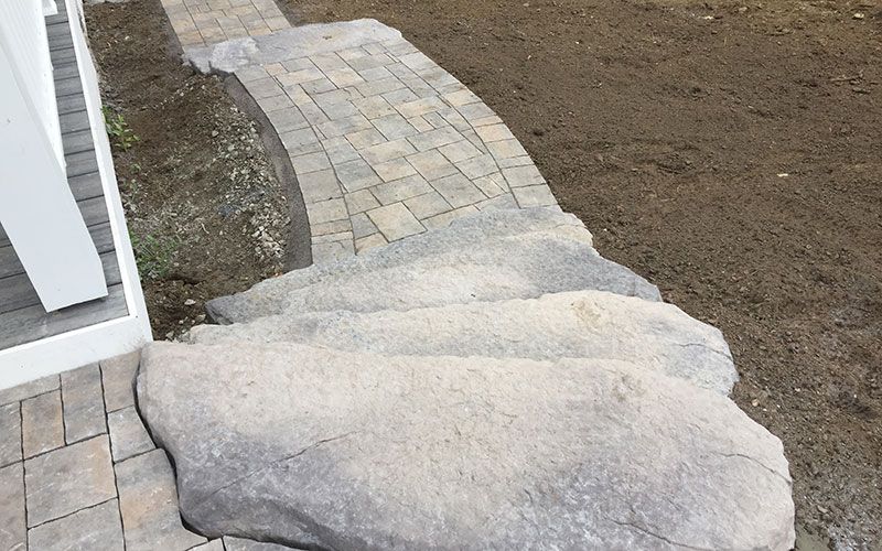 A stone walkway with a large rock in the middle of it.
