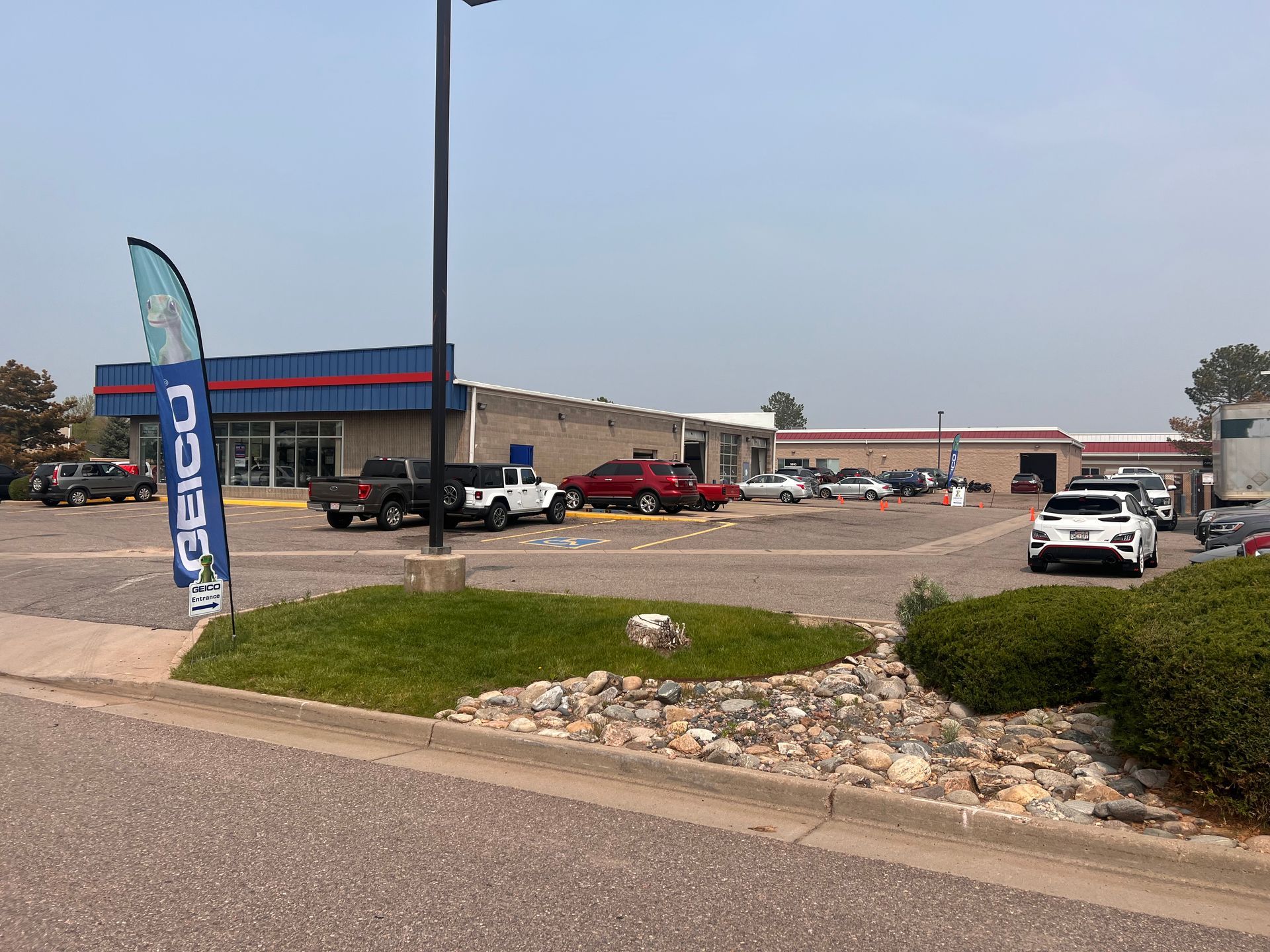A lot of cars are parked in a parking lot in front of a building.