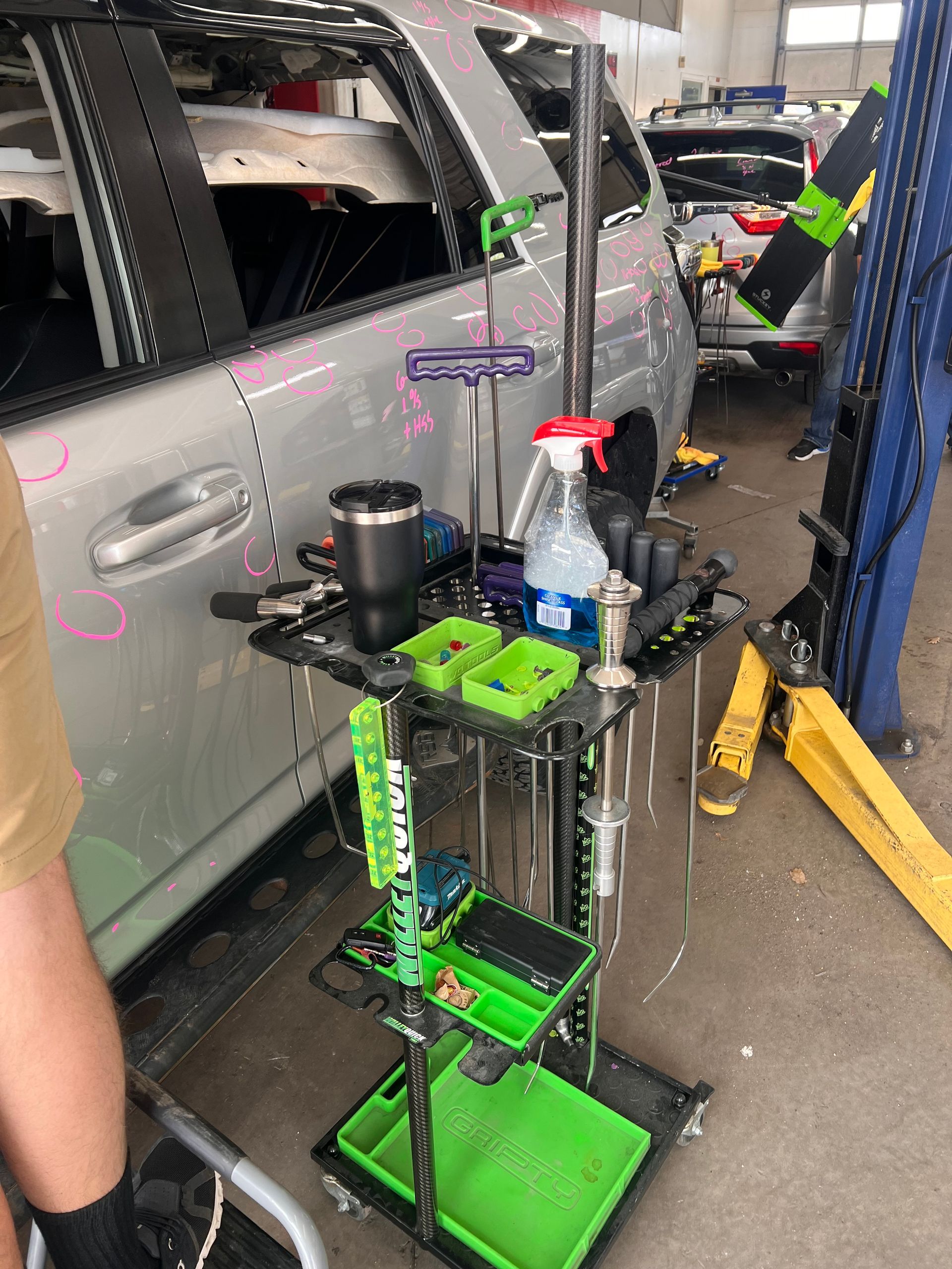 A car is sitting on a lift in a garage next to a tool cart.