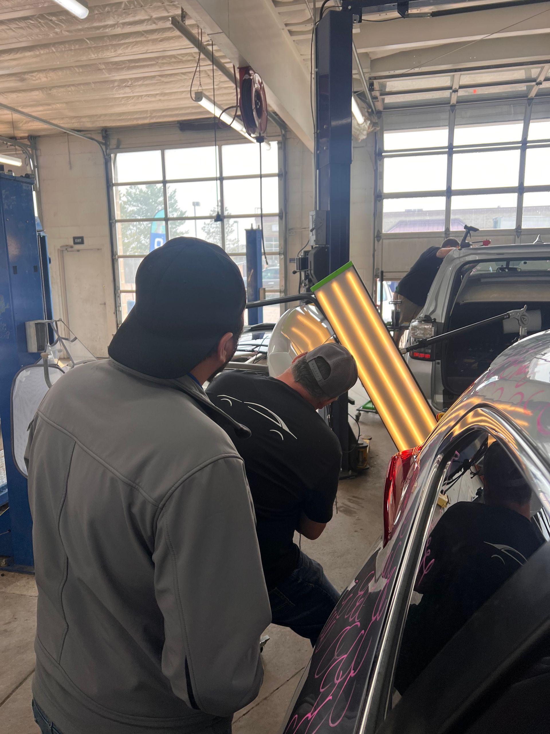A group of men are working on a car in a garage.