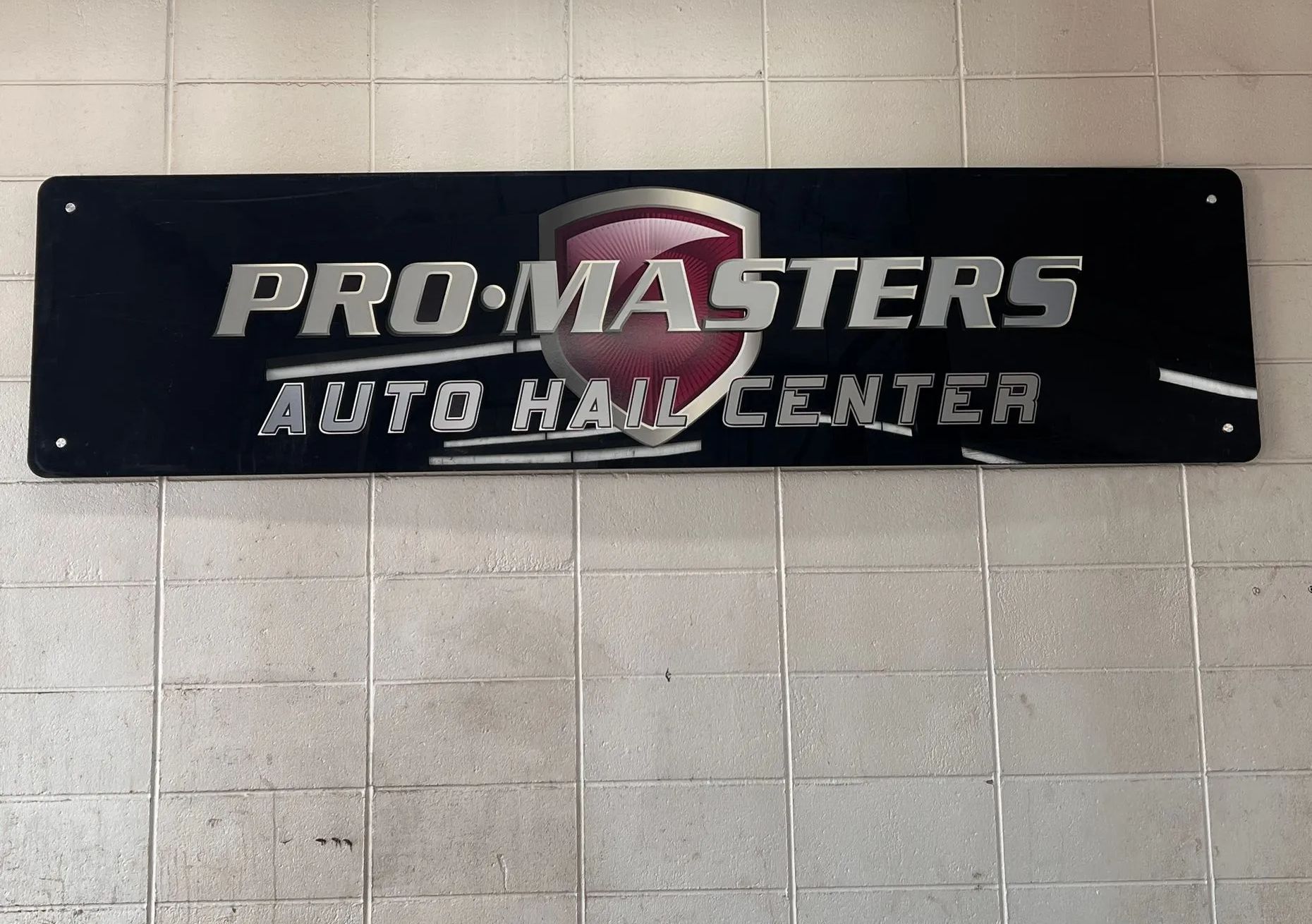A pro masters auto repair center sign hangs on a brick wall
