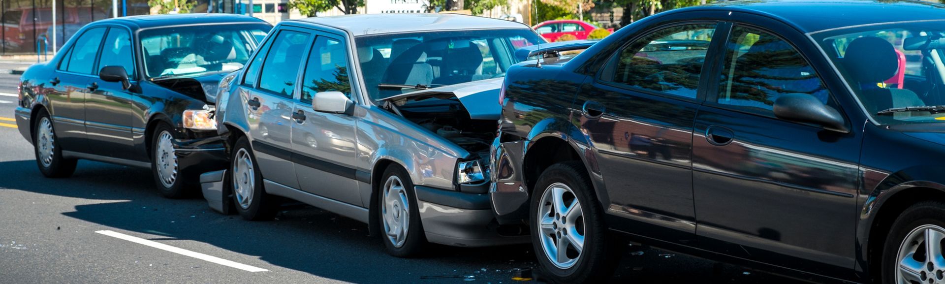 A row of cars are parked on the side of the road.