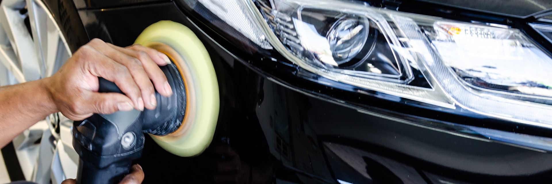 A person is polishing a car with a polisher.