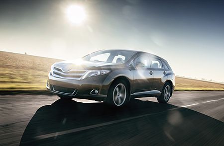 A car is driving down a road with the sun shining through the windshield.