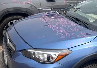 A blue subaru is parked next to a gray suv.