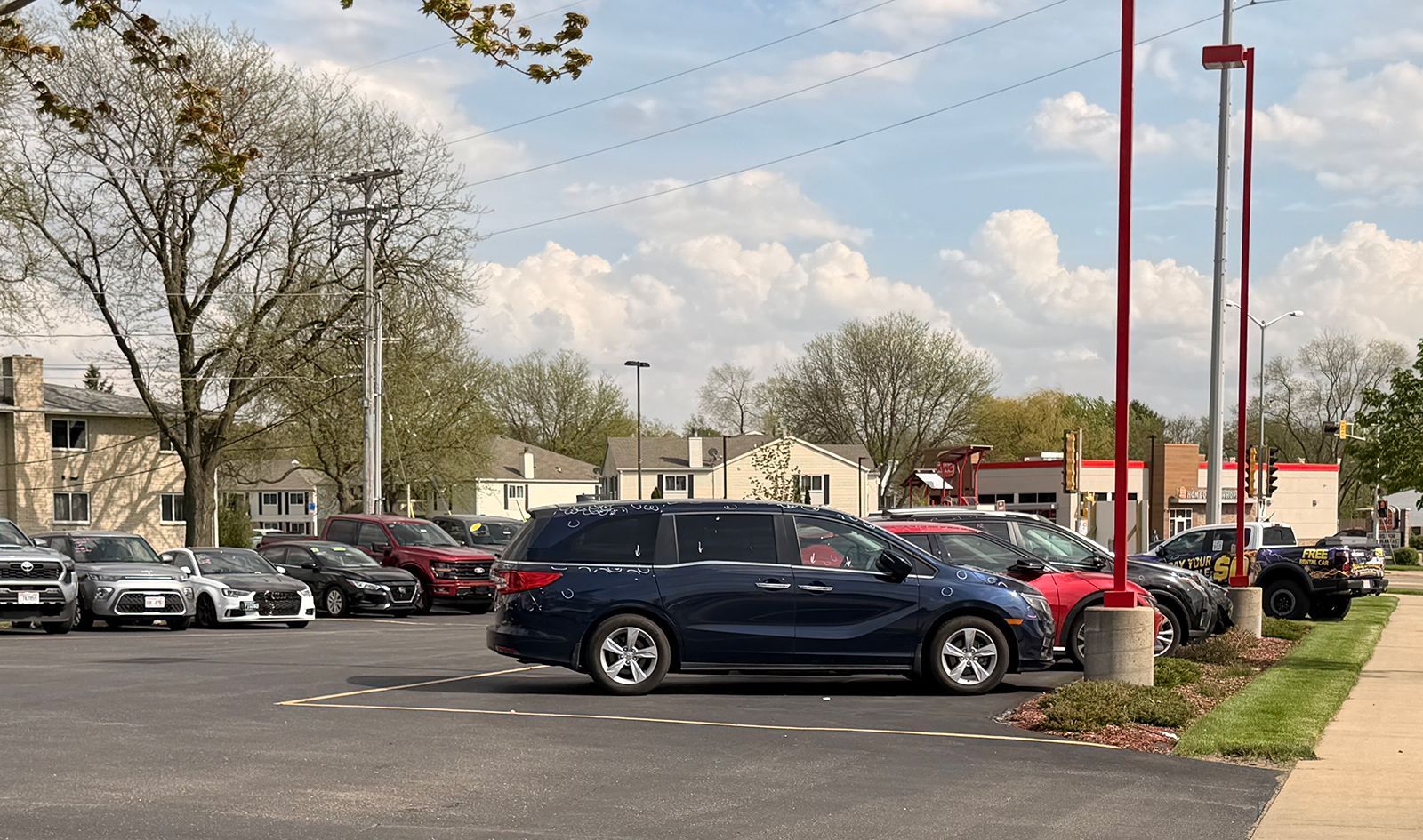 Parking lot with cars and leafless trees under a cloudy sky